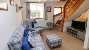 A living room with a sofa set, a television, and a staircase. - The Stable (Haverfordwest)