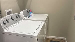 Ein Waschbereich mit zwei weißen Whirlpool-Waschmaschinen, einem roten Eimer und einer schwarzen Matte.