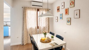 Un comedor con una mesa lista para dos comensales, una lámpara colgante y una pared decorada con cuadros.