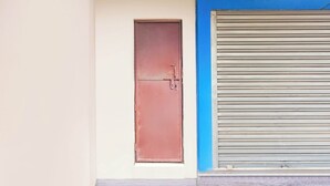 A closed red door with a metal handle and a blue shutter door.