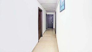 A corridor with white walls, a tiled floor, and doors on both sides.