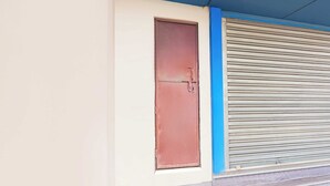 A closed brown door with a metal handle and a blue painted wall.