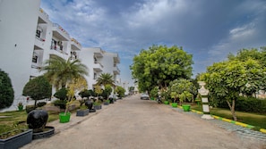A residential street with white buildings, green potted plants, and a clear sky.
