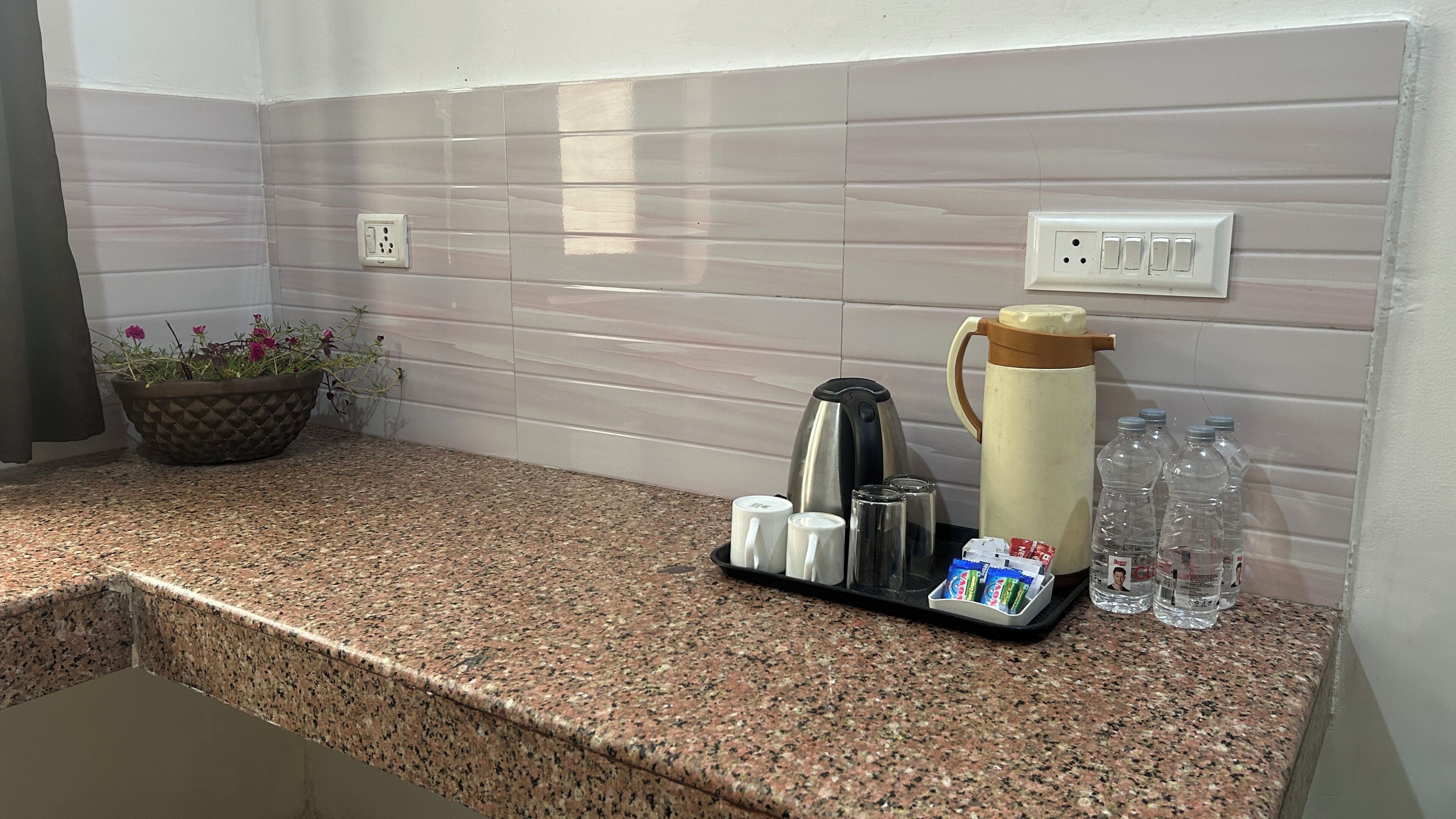 A kitchen counter with a coffee maker, mugs, a thermos, and bottled water.