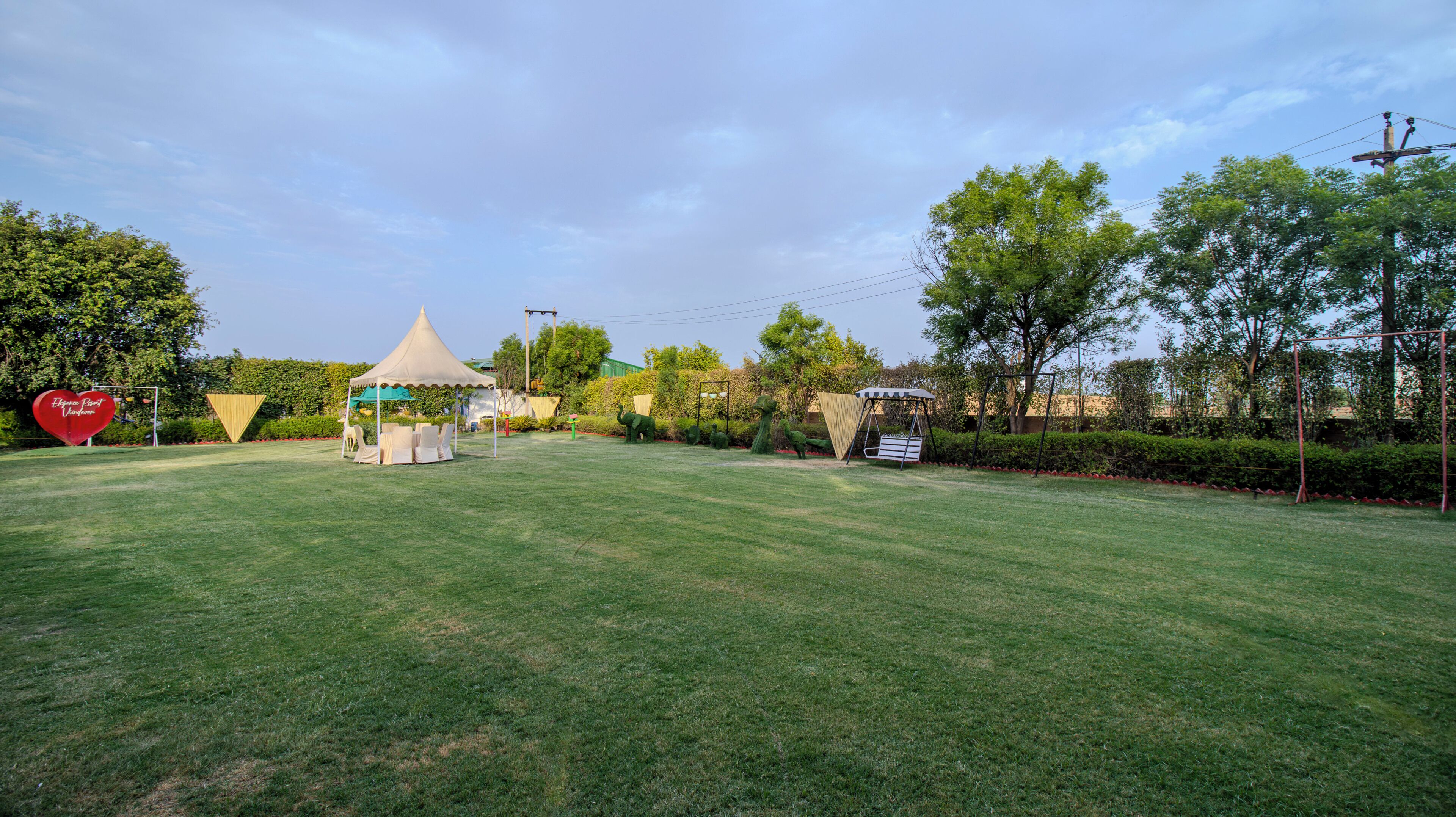 Uma área gramada bem cuidada, com um gazebo, assentos e um balanço.