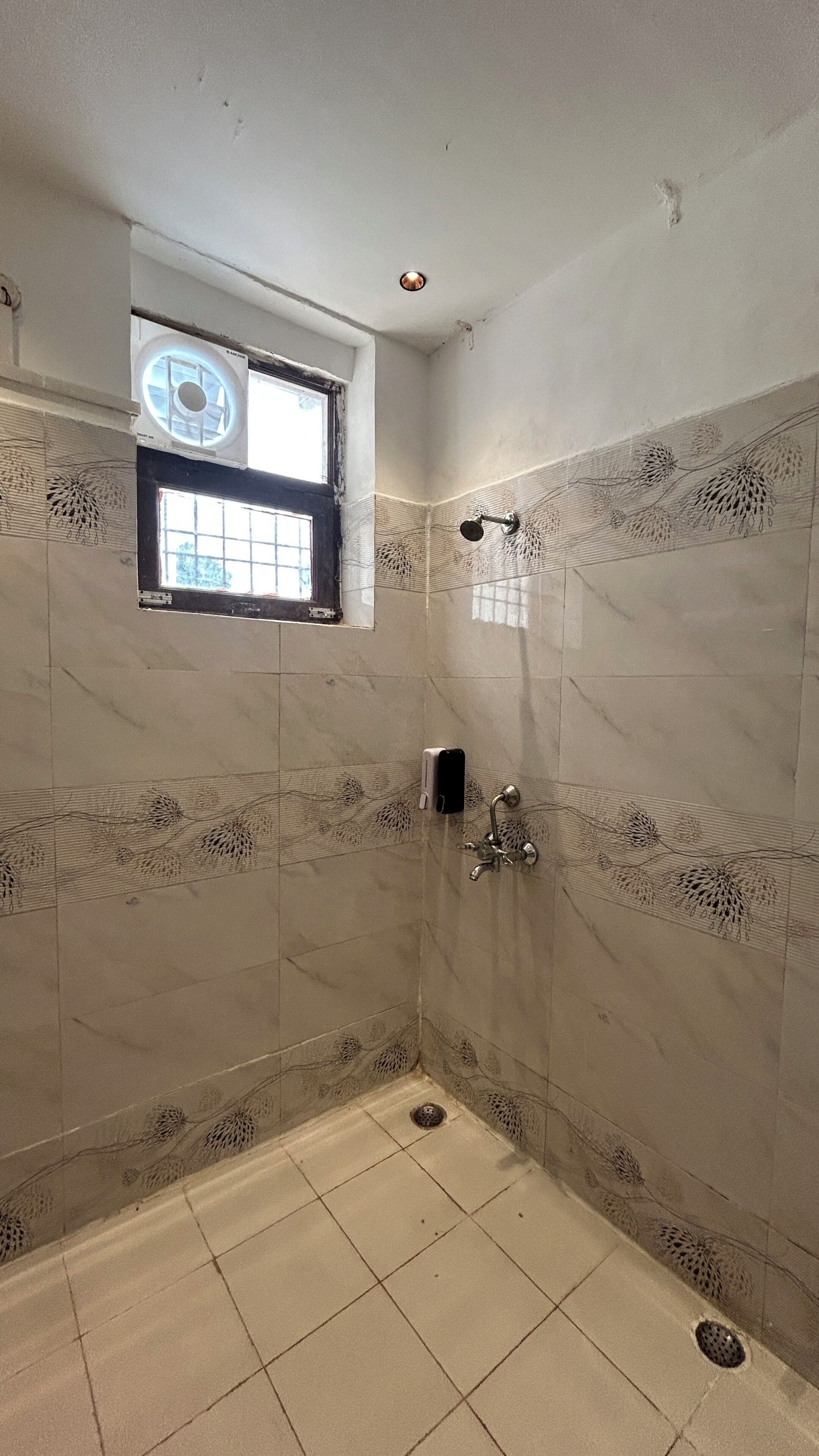 A bathroom with a shower, a window, and a hand dryer.