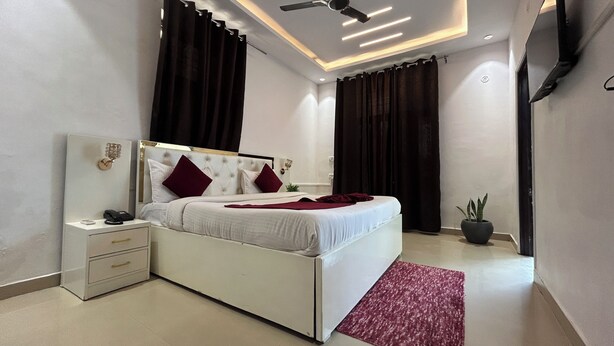 A modern bedroom with a bed, nightstand, and a potted plant. - Elegance Resort, Vrindavan (Vrindavan)