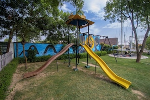 A playground with two slides and a climbing structure.