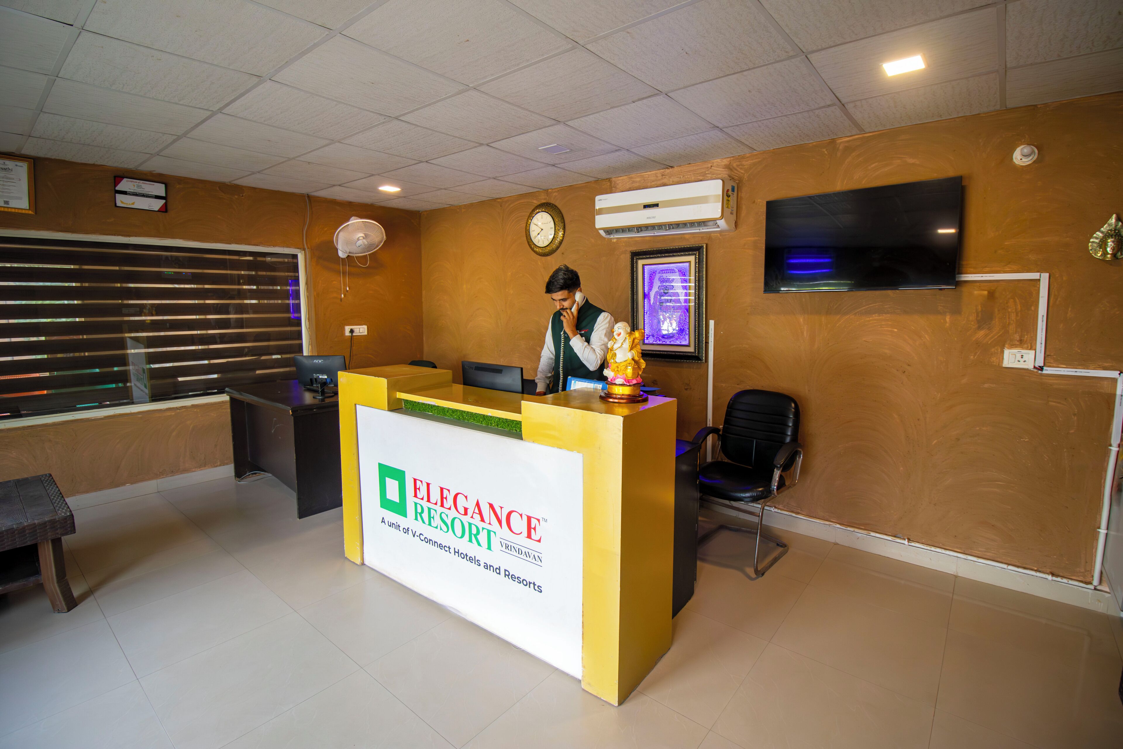 A reception desk with a sign for 'Elegance Resort' and a clock on the wall.
