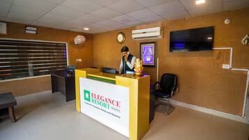 A reception desk with a sign for 'Elegance Resort' and a clock on the wall.