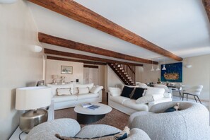 A modern living room with a staircase, white sofas, a round coffee table, and a painting on the wall. - Elegance and comfort in the heart of Venice – Canal view in San Marco (Venice)