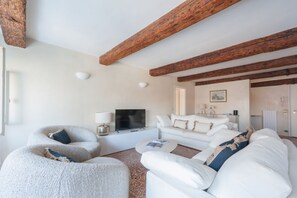 A modern living room with a white sofa, a curved armchair, a flat-screen TV, and a fireplace. - Elegance and comfort in the heart of Venice – Canal view in San Marco (Venice)