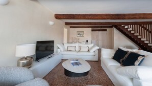 Ein Wohnzimmer mit einem weißen Sofa, einem Couchtisch, einem Fernseher und einer Lampe.