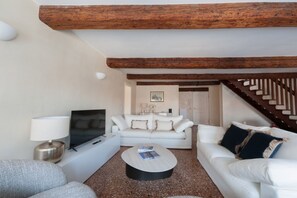 Ein Wohnzimmer mit einem weißen Sofa, einem Couchtisch, einem Fernseher und einer Lampe.