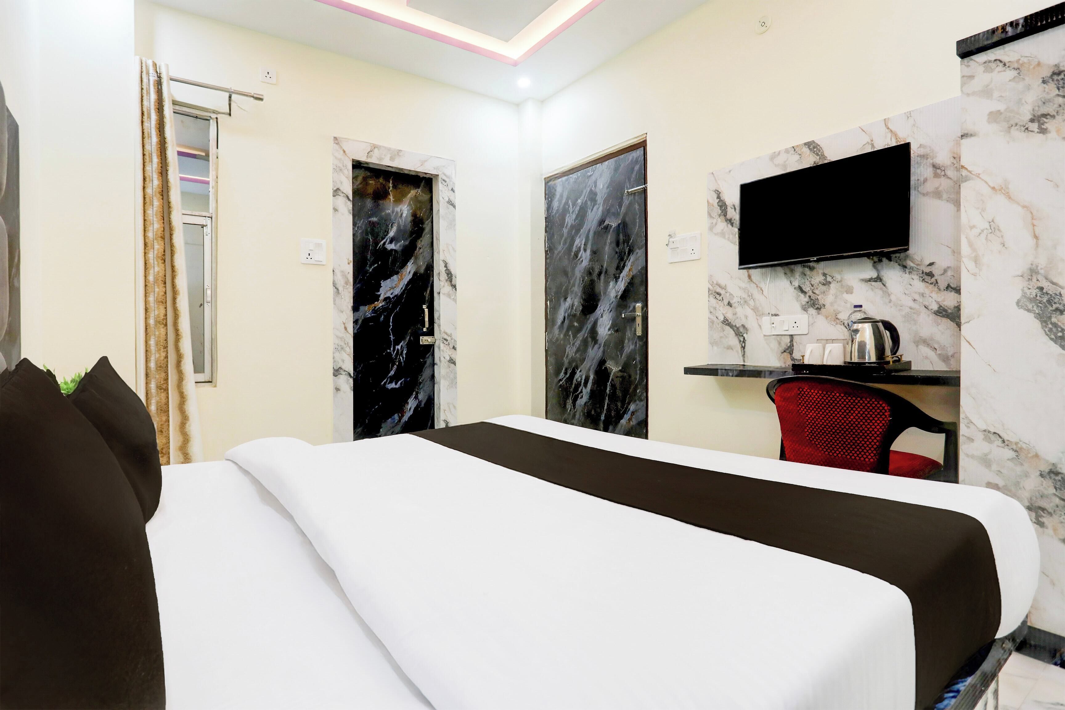 Hotelkamer met een bed, een bureau met stoel, een televisie en een marmeren wand.
