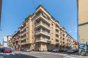 A multi-story residential building with balconies, a no entry sign, and parked cars. - A modern 57sqm flat, perfect for 4 guests, located on the first floor of a building with an elevator (stairs to reach it).The property is situated in the San Salvario district, one of Turin's central neighborhoods, renowned for its Art Nouveau and Baroqu (Turin)