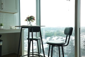Eine Küche mit Fensterblick auf die Stadt, ein Tisch mit Blumenvase und zwei Barhocker.