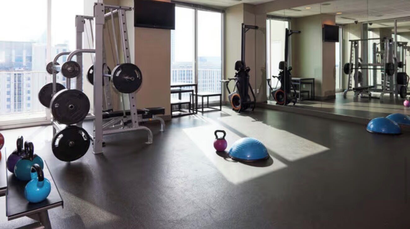 A gym with exercise equipment, a large window, and a mirror.