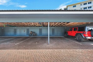 A parking garage with a red vehicle and a bicycle. - Harborside Gardens at the Moorings (Naples)