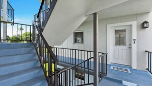 A residential building with a staircase, a white door, and a small window. - Harborside Gardens at the Moorings (Naples)