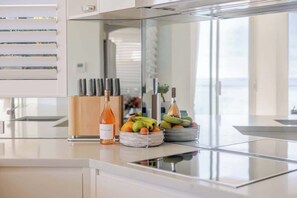 Een moderne keuken met een roestvrijstalen aanrecht, een fruitschaal met bananen en sinaasappels, en een fles wijn.