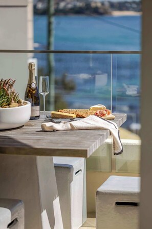 A dining table with a bottle of wine, a glass, and a variety of food items. - Luxury Waterfront Living at Fairy Bower (Manly)