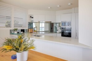 A modern kitchen with white cabinetry, stainless steel appliances, and a central island. - Luxury Waterfront Living at Fairy Bower (Manly)
