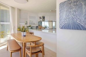 A modern kitchen with a central island, wooden furniture, and a large window providing natural light. - Luxury Waterfront Living at Fairy Bower (Manly)
