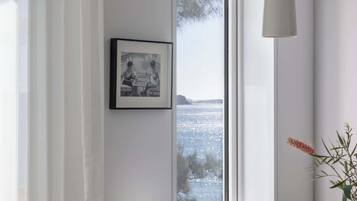 A dining area with a table, chairs, a bench, a picture on the wall, a window with a view, and a pendant light.