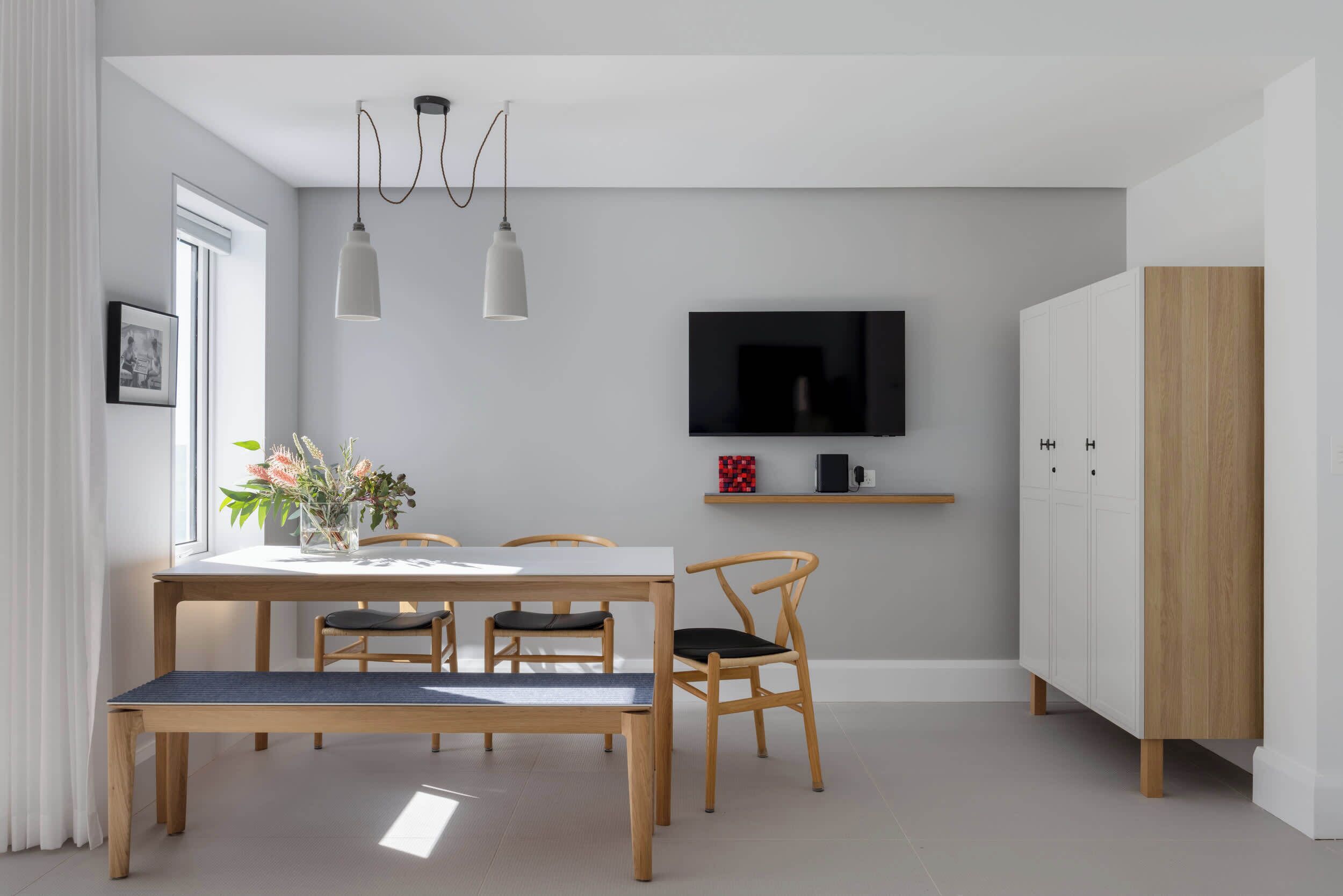 A modern dining area with a wooden table, chairs, and pendant lights.