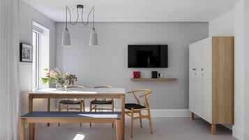 A modern dining area with a wooden table, chairs, and pendant lights.