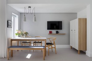 A modern dining area with a wooden table, chairs, and pendant lights. - Bower Break at Fairy Bower (Manly)