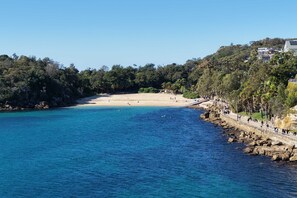 A coastal beach with clear blue waters, a sandy shore, and a rocky coastline. - Bower Break at Fairy Bower (Manly)