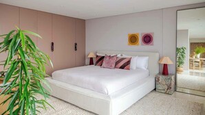 A modern bedroom with a large bed, bedside lamps, and a plant. - Solaris - Oceanfront location with clifftop views (Vaucluse)