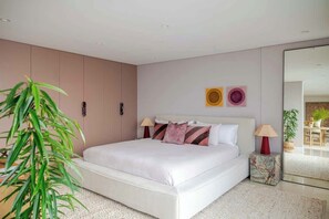 A modern bedroom with a large bed, bedside lamps, and a plant. - Solaris - Oceanfront location with clifftop views (Vaucluse)