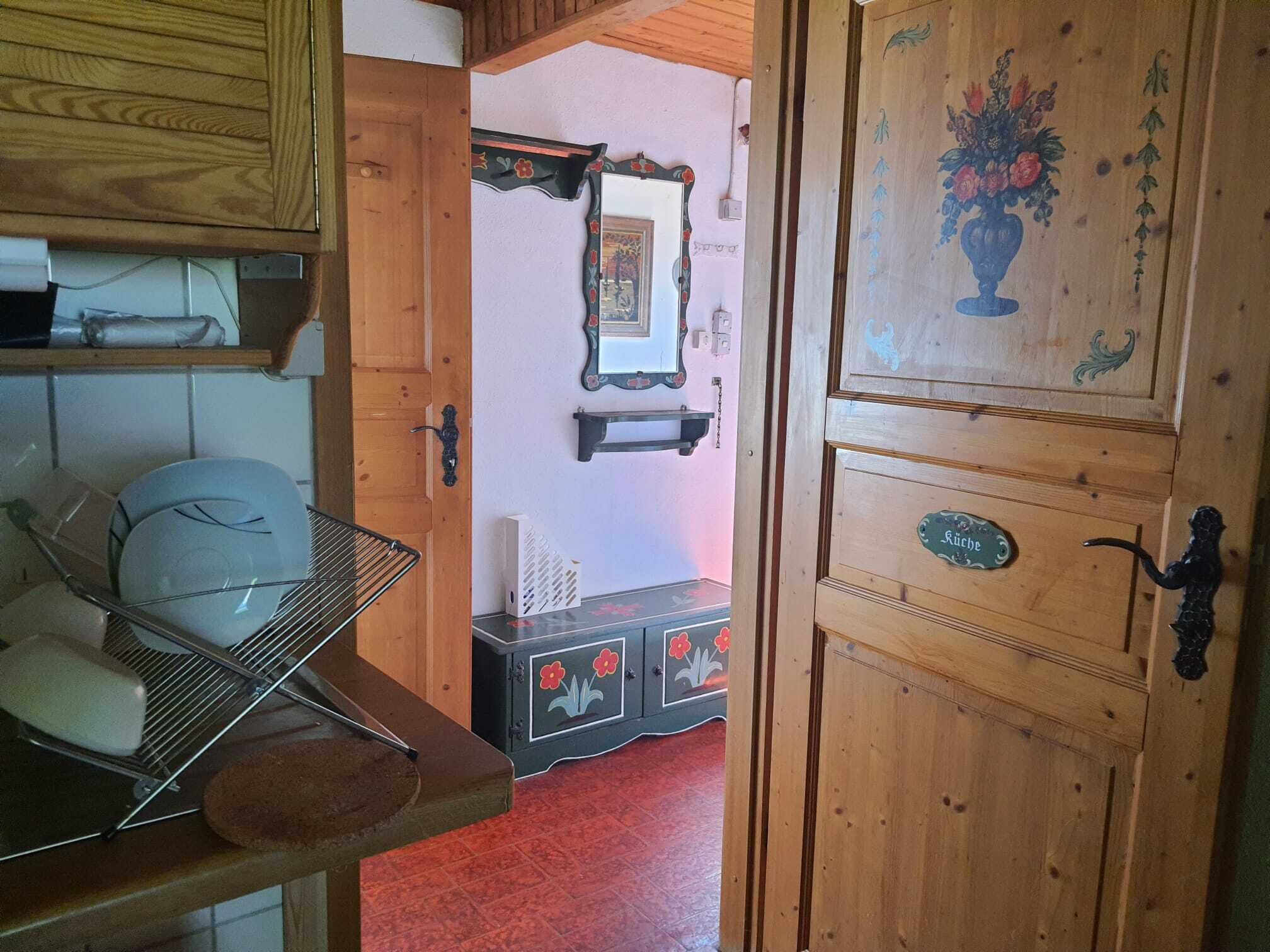 Ein Holzinnenraum mit einem Metallregal, einem Schrank mit floralen Verzierungen und einer Tür mit Namensschild.