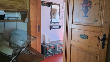 Un intérieur en bois avec une étagère en métal, un meuble orné de motifs floraux et une porte avec une plaque nominative.