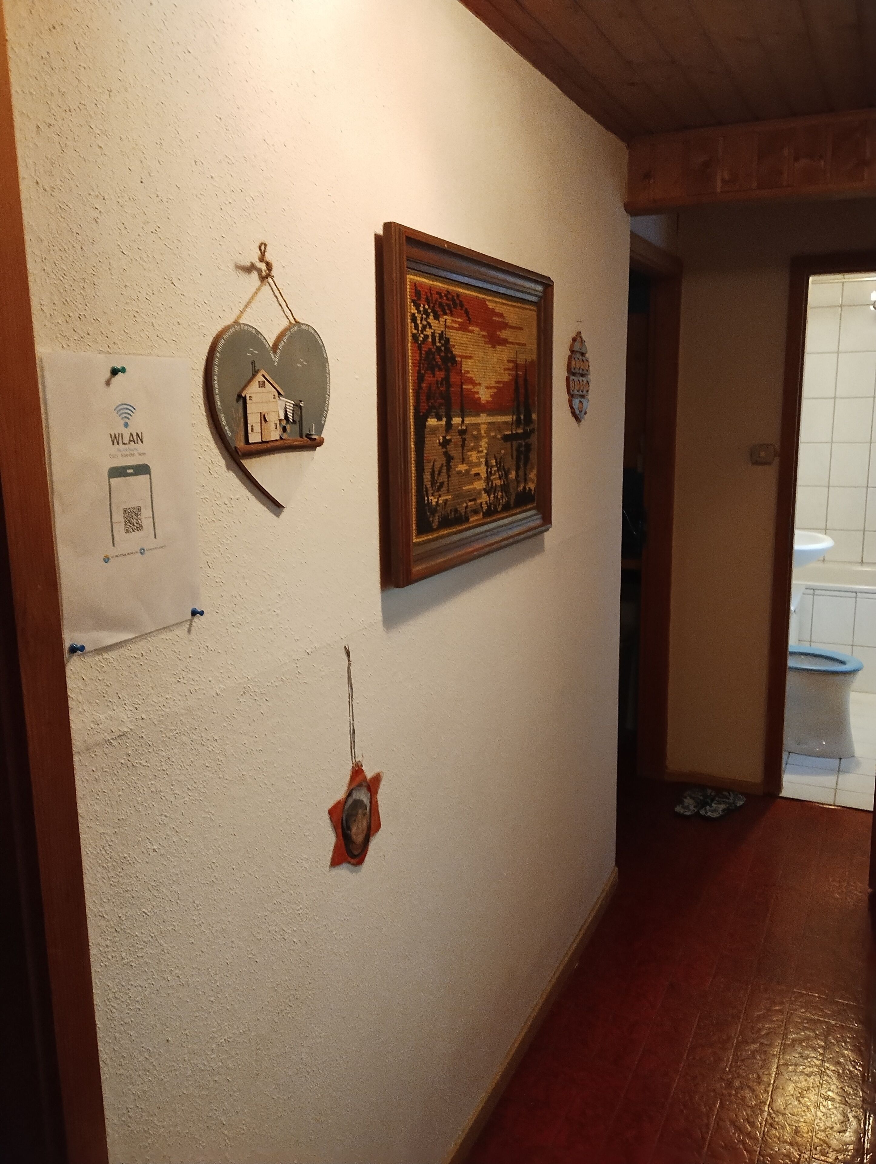 A hallway with a wooden ceiling, a framed painting, and a sign with a QR code.