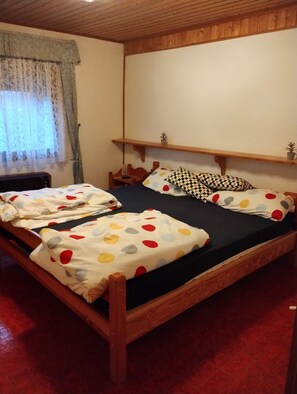A wooden bed with a black mattress, a wooden headboard, and a small shelf above.