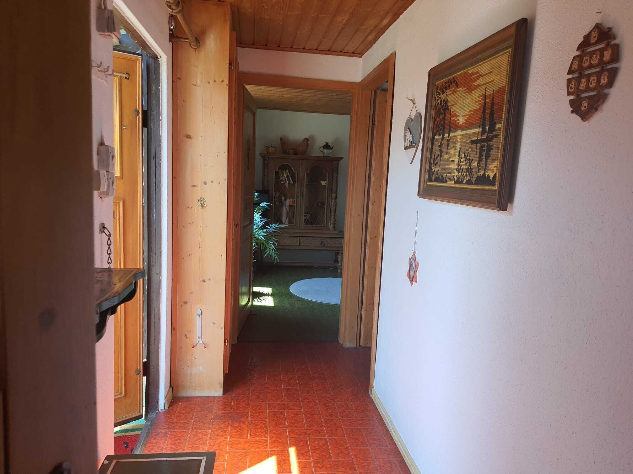 A hallway with a wooden door, a cabinet with glass doors, and a framed picture on the wall.