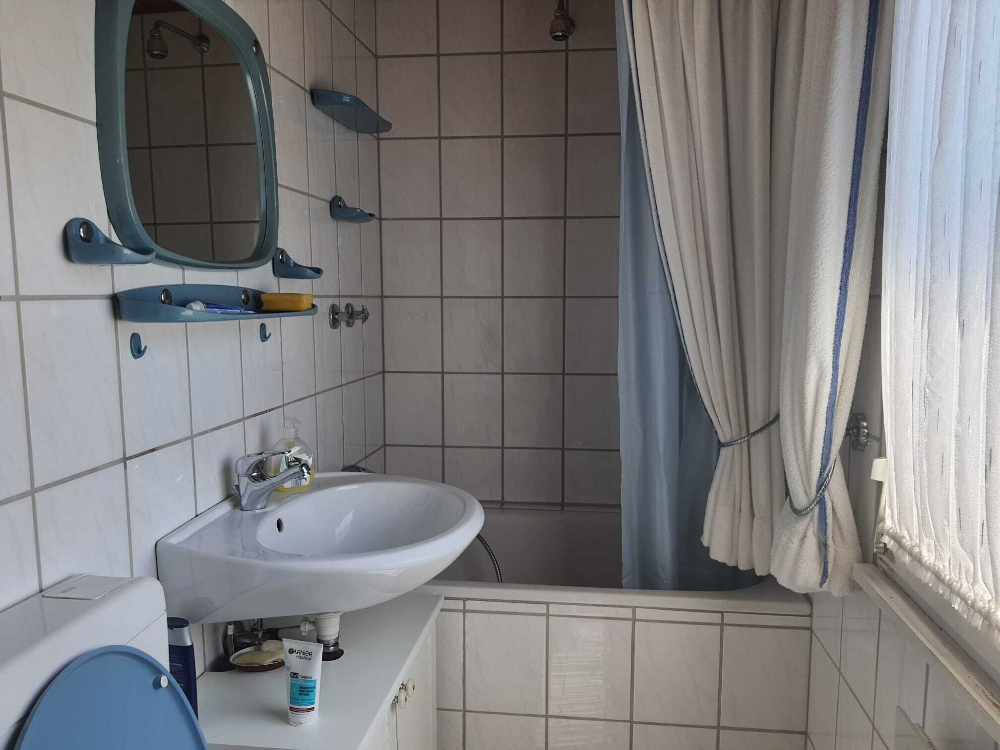 Een badkamer met een wit wastafel, een spiegel en een douchegordijn.