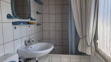 Een badkamer met een wit wastafel, een spiegel en een douchegordijn.