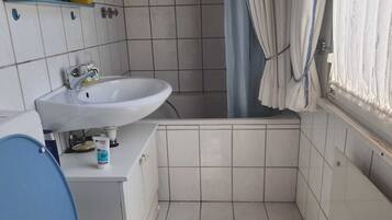 Ein Badezimmer mit einem weißen Waschbecken, einer blauen Toilette und einer Duschkabine.