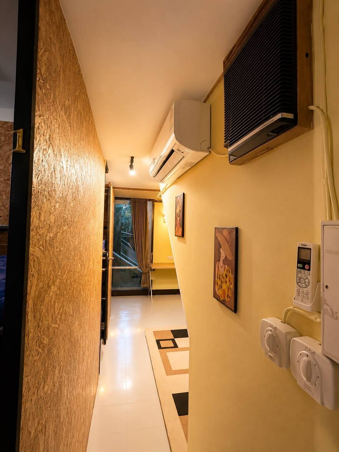Et hotelkorydor med en aircondition, en telefon og et billede på væggen.