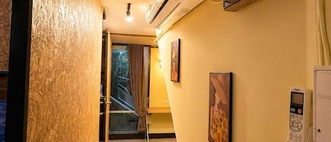A hotel hallway with an air conditioning unit, a telephone, and a painting on the wall.