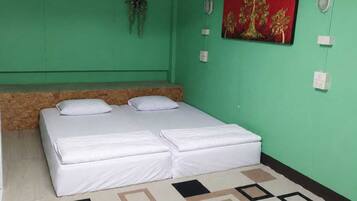 A room with a bed, a ceiling fan, an air conditioning unit, a wall-mounted light, and a decorative painting.