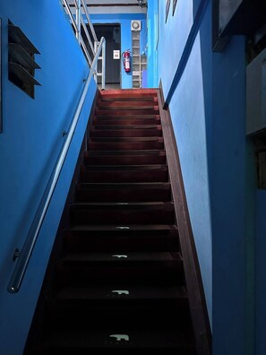 A staircase leading to a second floor with blue walls and a fire extinguisher on the wall. - J cafe & hostel (Chiang Mai)