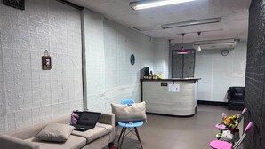 Una habitación con sofá, escritorio, silla y una pequeña mesa con flores.