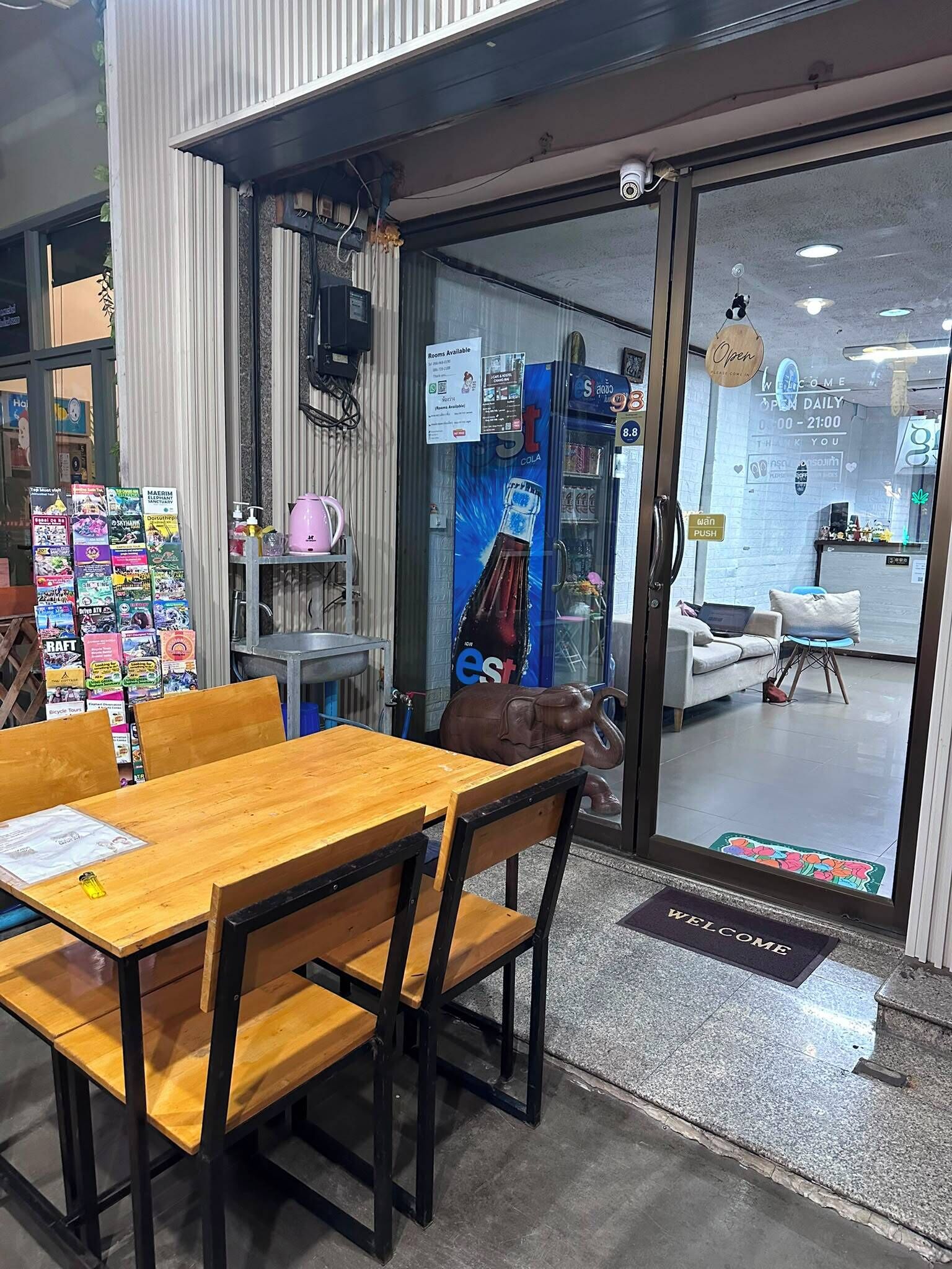 A cafe with a wooden table and chairs, a glass door entrance, and a sign indicating room availability.