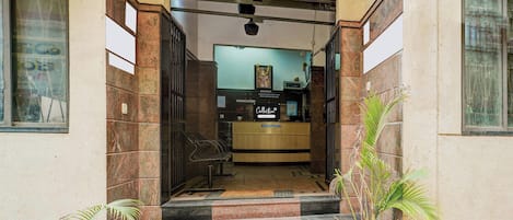 Ein Empfangsbereich mit einer Rezeption, einer Treppe zu einer oberen Etage und Zimmerpflanzen.